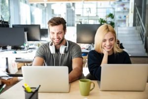 sonrientes-colegas-jovenes-sentados-coworking-oficina_171337-17679.jpg